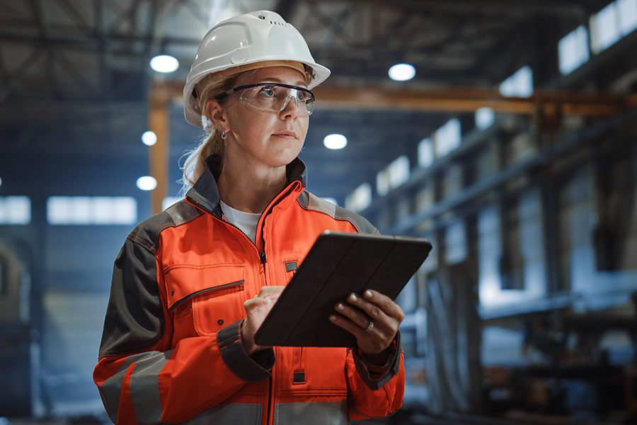 Specizlized Business Insurance - Closeup Portrait of a Young Woman Standing in a Manufacturing Facility While Holding a Tablet in Her Hands