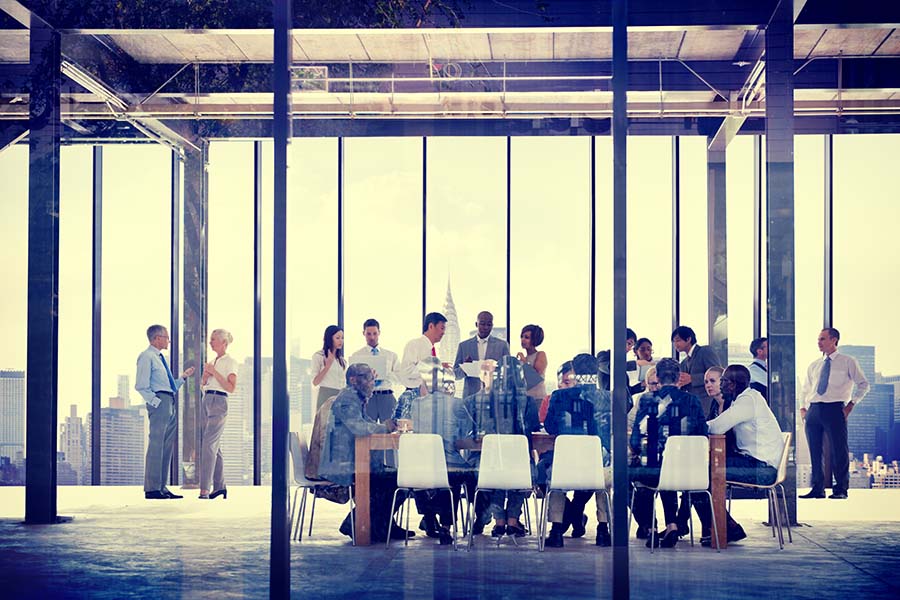 Professional Services Insurance - View of People Sitting in Meeting Room During a Large Company Business Meeting with Views of the City in the Background