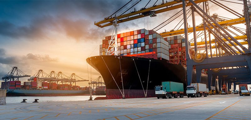 Ports and Terminals - Ship with Cargo Pulled into a Port with Large Cranes at Sunset on a Nice Day